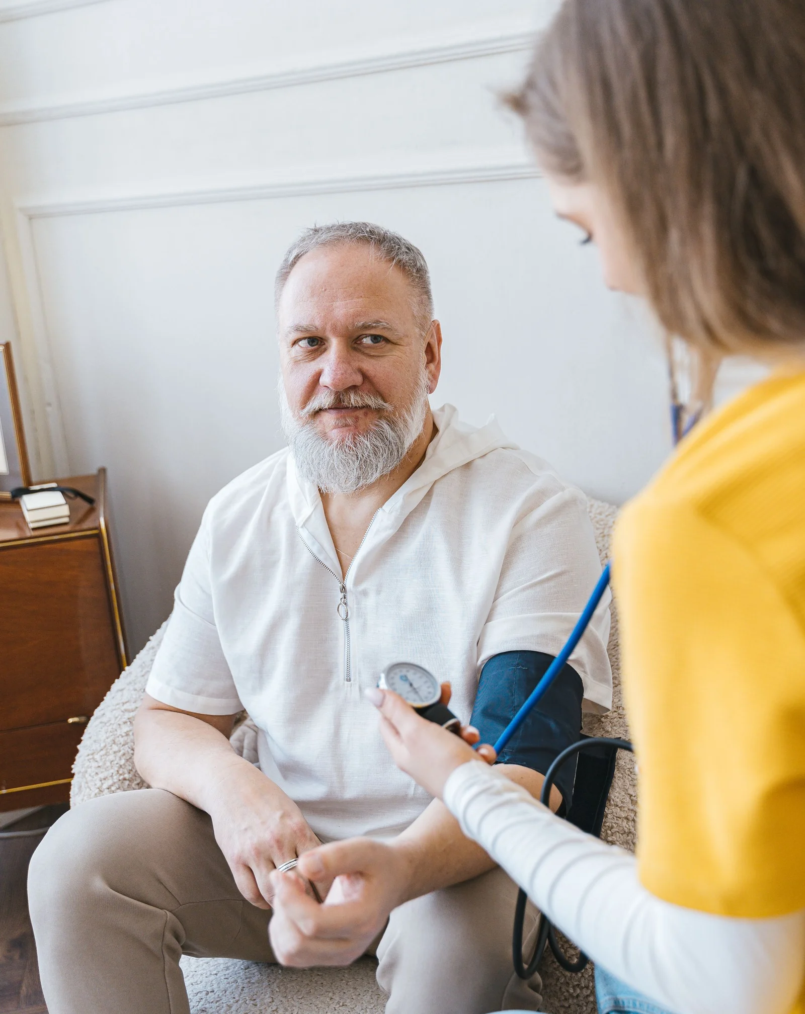 A home health nurse checking an older man's blood pressure at home