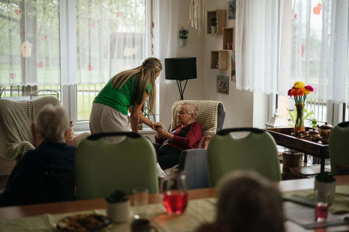 A caregiver assisting older adults with tea